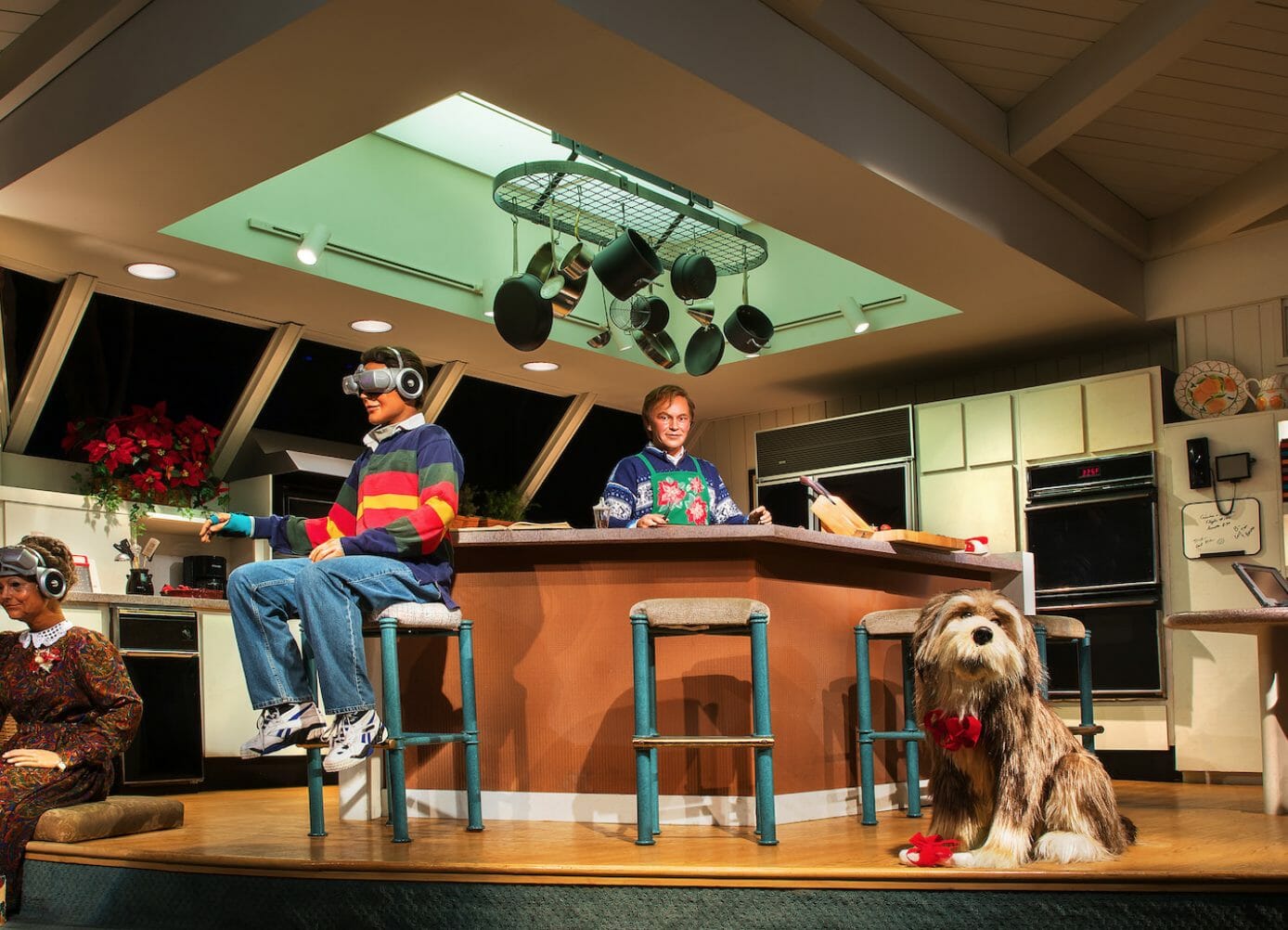 a scene from the carousel of progress' last section proposing a future. an animatronic boy sits on a counter wearing a vr headset while an animatronic dog sits in the foreground and another humanoid animatronic stands in the background
